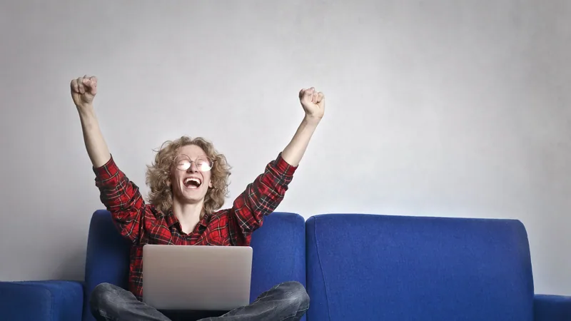 Person celebrating on laptop receiving credit card approval milestone