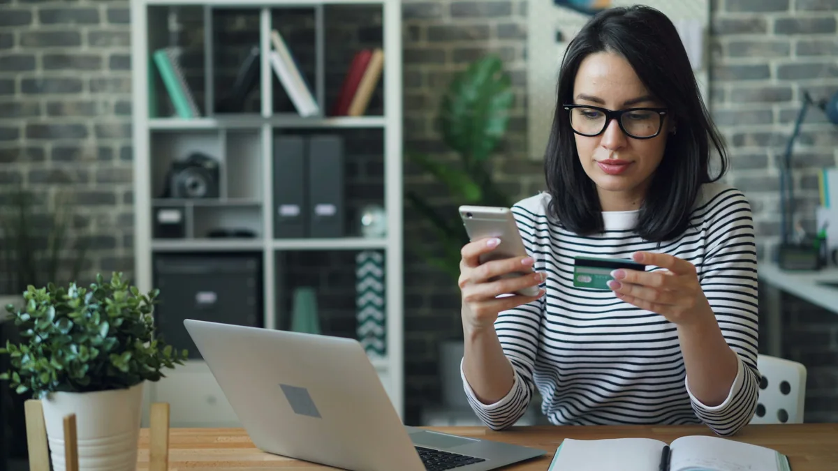 Woman using smartphone and credit card for mobile banking app
