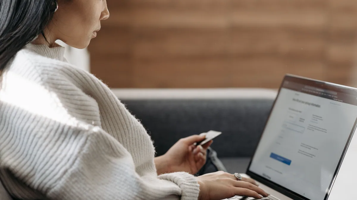 Woman holding credit card applying online using laptop at home